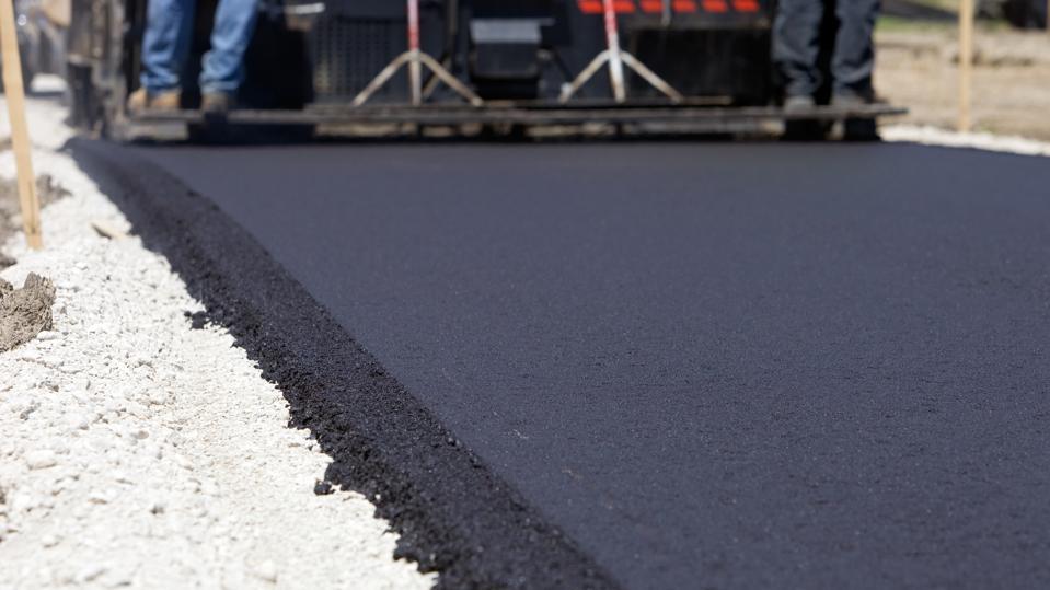 Paver machine laying fresh hot-mix asphalt on a prepared gravel base